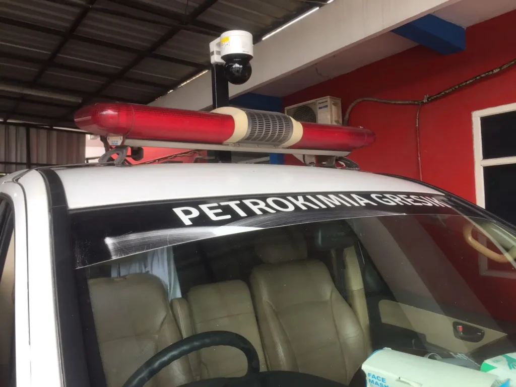 Tampilan close-up kamera CCTV PTZ Mobile yang terpasang rapi di belakang lampu rotator pada atap kendaraan operasional Petrokimia Gresik.