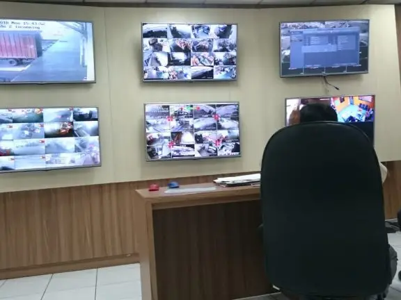 Ruang kontrol monitor CCTV security system dengan teknisi sedang memantau 6 layar DVS di kantor pusat layanan CCTV di Surabaya. Solusi pemantauan keamanan 24 jam