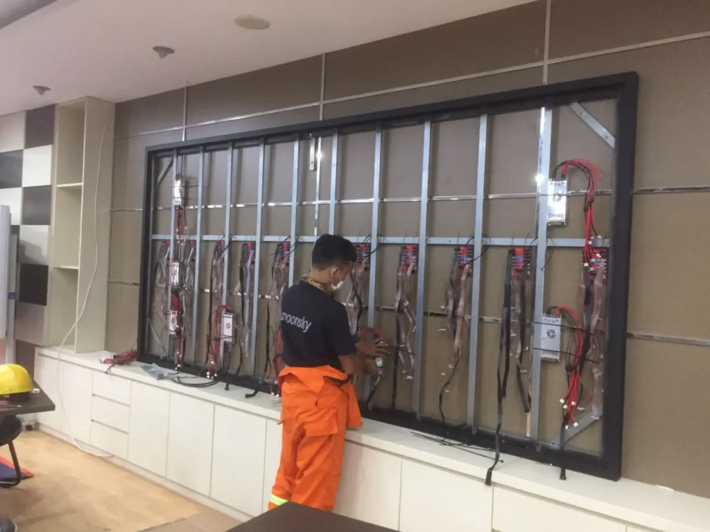 Teknisi CCTVSurabaya.com melakukan perakitan jalur kabel dan modul LED Videotron Indoor di ruang rapat kantor instansi Surabaya.