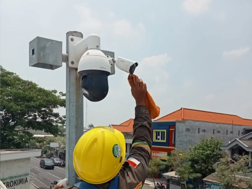 Teknisi CCTVSurabaya.com dengan alat pelindung diri (APD) lengkap melakukan pembersihan lensa dan maintenance kamera CCTV PTZ Outdoor di Jalan Urea Raya, kawasan Petrokimia Gresik.
