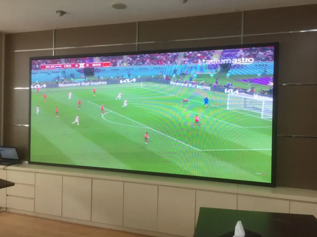 Tampilan layar Videotron Indoor jernih dan smooth menampilkan pertandingan sepak bola di ruang rapat kantor instansi Surabaya, bukti kualitas refresh rate tinggi.